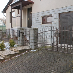 Schmiedeeiserne Umzunung eines Einfamilienhauses  geschmiedeter Zaun mit verdichteten Elementen im unteren Teil 