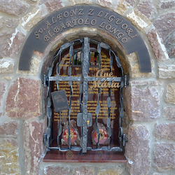 Schmiedeeisernes Heiligendenkmal  Inschrift, Gitter und Zeichen. St. Alfonz von Liguori: Das Buch; Bartolo Longo: Ave Maria
