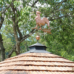 Copper rooster on a forged roof  summer gazebo near the family house