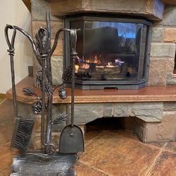 An artistic fireplace tool set with the conifer theme for pleasant autumn and winter evenings by afireplace