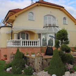Přikrytí terasy rodinného domu kovaným přístřeškem v bílé barvě