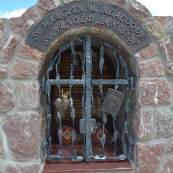 Kovaný památník. Sv. Margita M. Alacoque - srdce s plamenem, křížem a trnovou korunou, Sv. Arnold Janssen - Bible