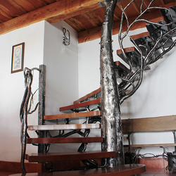 Kunstvolle Treppe mit Geländer in Form eines Baumes, hergestellt aus natürlichen Werk-stoffen, Metall und Holz – modernes Geländer