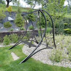 Wrought-iron garden swing in the garden of a family house – forged swing