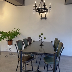 Table en fer forgé en planche de granit couleurs noire-verte, les chaises habillées en cuir bovin d’origine italienne