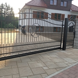 Posuvná kovaná brána s bránkou v jednoduchom štýle pri rodinnom dome