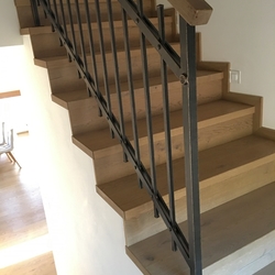 Geschmiedetes Geländer für die Treppe im Innenraum – einfaches Geländer mit einem hölzernen Handlauf