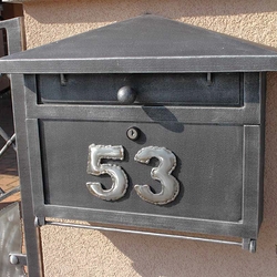A wrought iron post box with a number sign