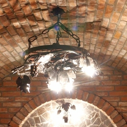 Grape chandelier in a wagon wheel as lighting for a wine cellar - luxury lamps